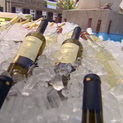 Weinflaschen liegen zum Kühlen im mit Eiswürfeln gefüllten Dorfbrunnen