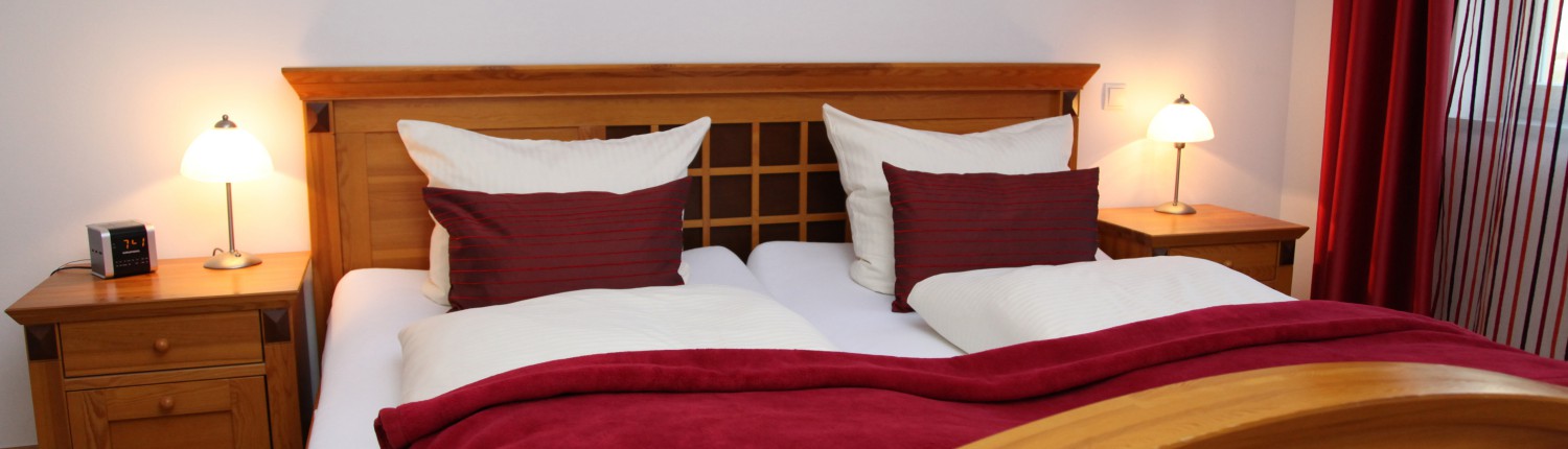 Stilvolles Naturholz-Doppelbett mit weißer und weinroter Bettwäsche