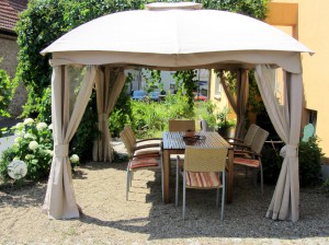 Gruppentisch mit Stühlen und Sitzkissen bequem im Schatten unter einem Pavillon im Weinhof