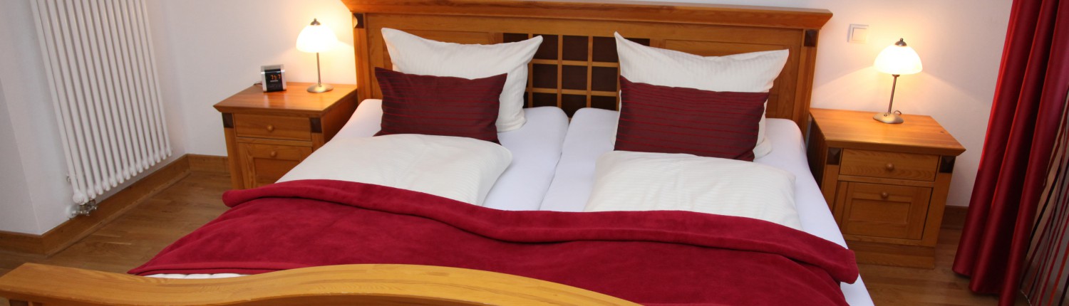 Stilvolles Naturholz-Doppelbett mit weißer und weinroter Bettwäsche